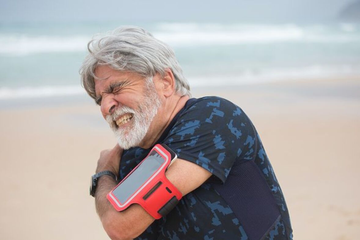 Man holding right shoulder grimacing in pain